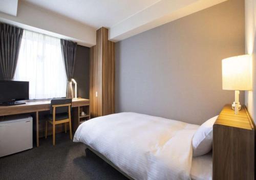 a hotel room with a bed and a desk with a computer at Business Inn Norte in Sapporo