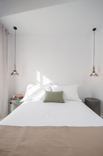 a bedroom with a large white bed with two pendant lights at Thomais Studios in Naxos Chora