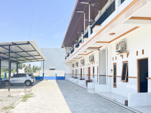 a building with a car parked in a parking lot at Elma Guesthouse YIA KulonProgo Yogyakarta Mitra RedDoorz in Yogyakarta