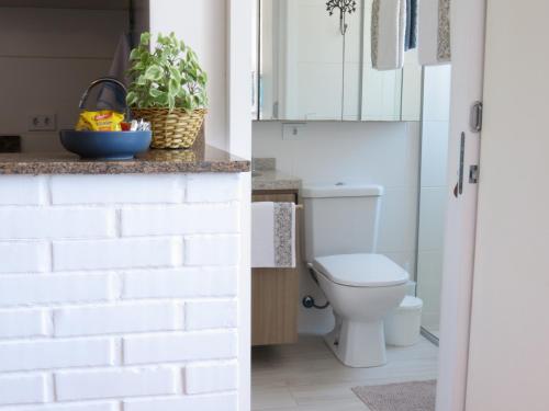 a bathroom with a toilet and a white brick wall at ESPAÇO AZUL Original in Curitiba
