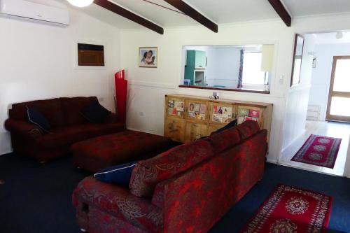 a living room with two red couches and a mirror at Creekside Cottage, country escape, Rumbellara farm in Yellingbo