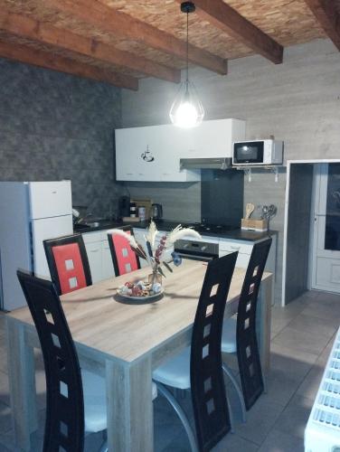 une cuisine avec une table en bois entourée de chaises. dans l'établissement jolie maison campagnarde, à Gevrolles