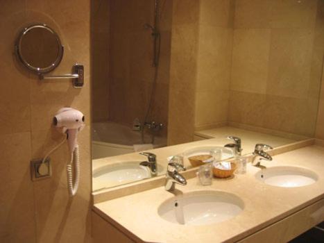 a bathroom with two sinks and a phone next to a mirror at Hotel Doña Urraca in Zamora