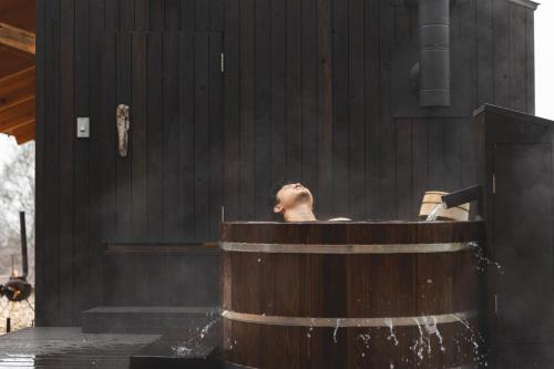 a man in a bath tub with his head at Earthboat Togakushi in Nagano