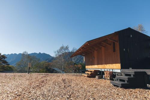 a large black barn sitting on top of a field at Earthboat Togakushi in Nagano