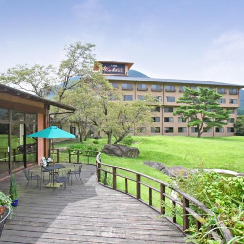 a boardwalk with tables and chairs and a building at Aso Baien Spa Resort in Minami Aso
