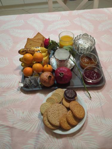 a table with a tray of cookies and fruit and biscuits at chambre simple proche aéroport in Pusignan