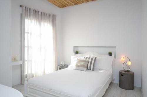 a white bedroom with a white bed and a window at Thomais Studios in Naxos Chora