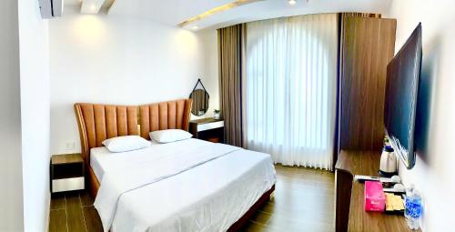 a bedroom with a bed and a flat screen tv at Times Hotel in Trảng Bàng