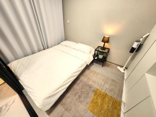 a small bedroom with a white bed and a lamp at Majestic Seoul Stay Central in Seoul