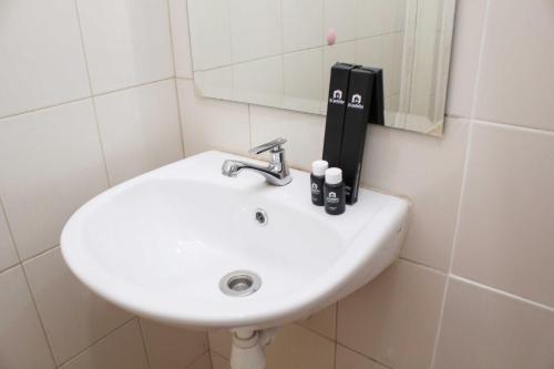 a white sink in a bathroom with a mirror at Nice and Elegant Studio at Riverview Jababeka Apartment By Travelio in Cikarang