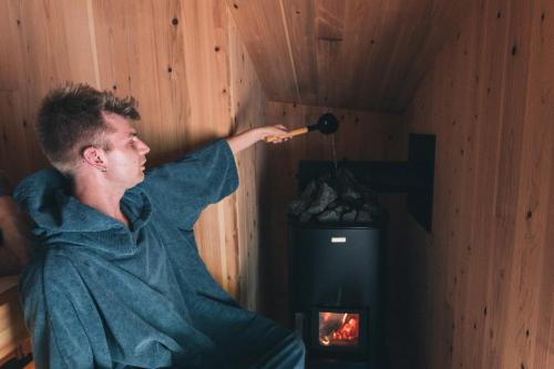 a man is standing in a room with a fireplace at Earthboat Togakushi in Nagano