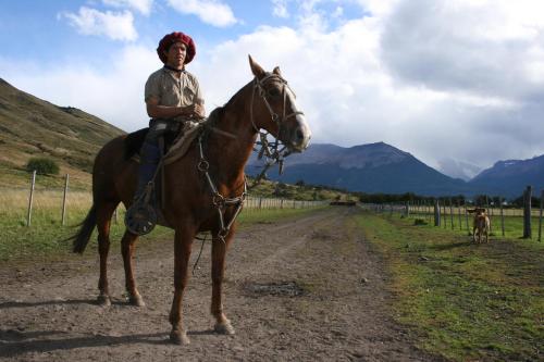 un joven sentado sobre un caballo en un camino de tierra en Estancia Nibepo Aike en Colonia Francisco Perito Moreno