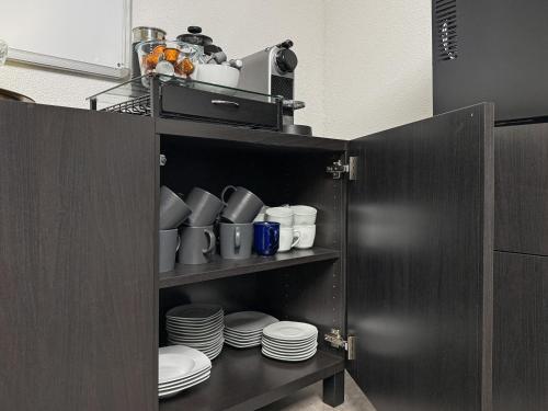 a cabinet with plates and cups and dishes in it at Gruppenfreundl Komfort Apt für 18 im Zentrum Stuttgarts in Stuttgart