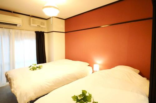 two beds in a room with a red wall at Shin Osaka Grand Heights SG21 in Osaka
