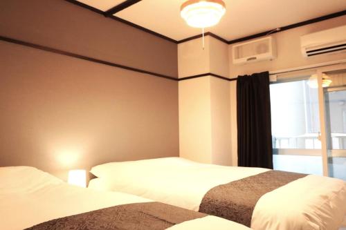 a hotel room with two beds and a window at Shin Osaka Grand Heights SG21 in Osaka