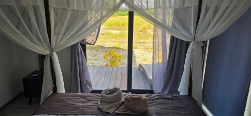 a bedroom with a bed with curtains and a window at Eagle Bay Retreat Borneo Beach Villas Beach Front in Kumbatang