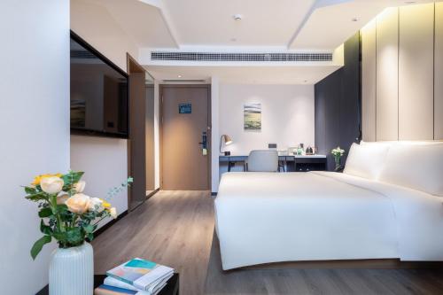 a bedroom with a white bed and a vase of flowers at Atour Hotel Chengdu Sichuan Normal University in Chengdu
