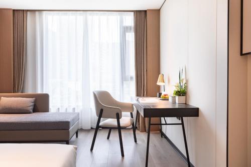 a hotel room with a desk and a bed and a bedroom at Atour Hotel Chengdu Sichuan Normal University in Chengdu