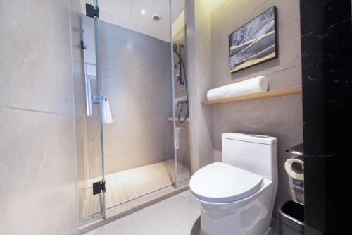 a bathroom with a toilet and a glass shower at Atour Hotel Chengdu Sichuan Normal University in Chengdu