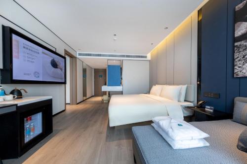 a hotel room with a bed and a flat screen tv at Atour Hotel Chengdu Sichuan Normal University in Chengdu