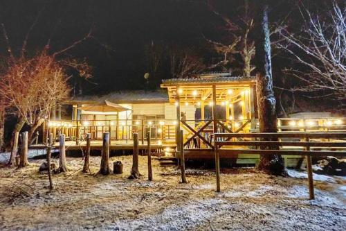 a log cabin with lights in the snow at night at コーボ in Yamanakako