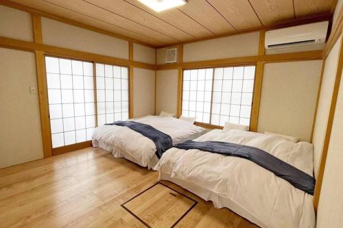 two beds in a room with two windows at コーボ in Yamanakako
