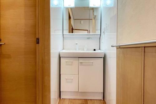 a bathroom with a white sink and a mirror at コーボ in Yamanakako