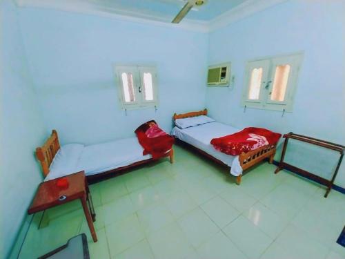 a room with two beds and a table and windows at Osiris Hotel Luxor in Luxor