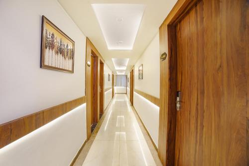 un largo pasillo con paredes blancas y una puerta de madera en FabHotel Bliss Residency, en Bhopal