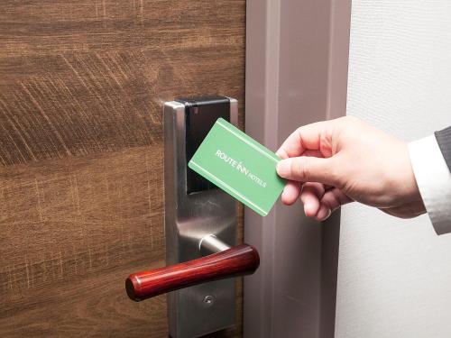 a person unlocking a door with a green card at Hotel Route Inn Okayama Maniwa in Maniwa
