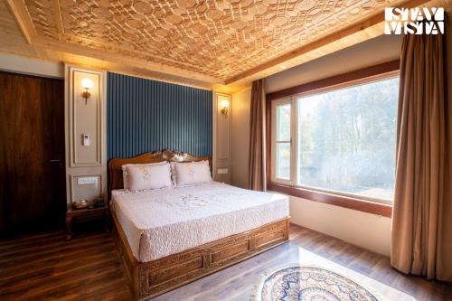 a bedroom with a bed and a large window at StayVista at Khwab Villa with Lawn, BBQ in Srinagar