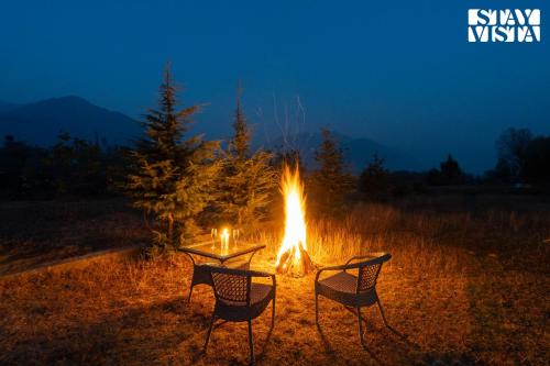 a fire pit with two chairs around it at night at StayVista at Khwab Villa with Lawn, BBQ in Srinagar