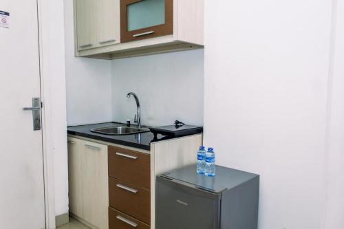 a small kitchen with a sink and a refrigerator at Comfort Stay Studio Room at Poris 88 Apartment By Travelio in Tangerang