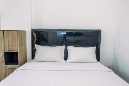 a bed with a black headboard with two white pillows at Comfort Stay Studio Room at Poris 88 Apartment By Travelio in Tangerang