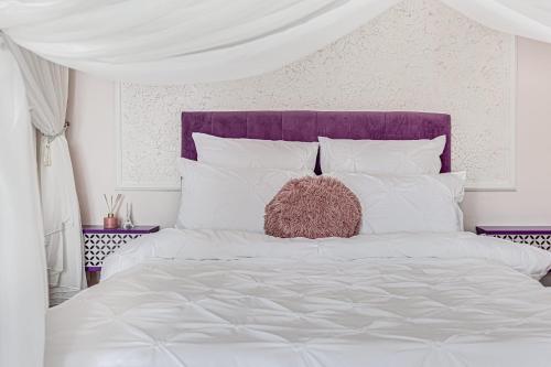 a white bed with a purple headboard and white pillows at ARI - ARED Luxurious Apartments with Balcony & Free Parking in Arad