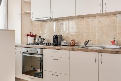 a kitchen with white cabinets and a sink at ARI - ARED Luxurious Apartments with Balcony & Free Parking in Arad