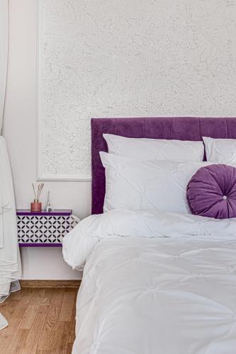 a white bed with a purple headboard and white pillows at ARI - ARED Luxurious Apartments with Balcony & Free Parking in Arad