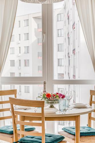 a table with flowers on it in front of a window at ARI - ARED Luxurious Apartments with Balcony & Free Parking in Arad