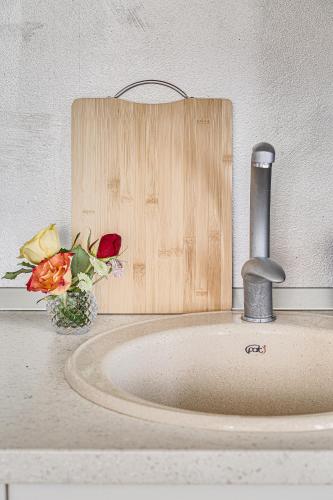 a sink with a faucet and flowers on a counter at ARI - ARED Luxurious Apartments with Balcony & Free Parking in Arad