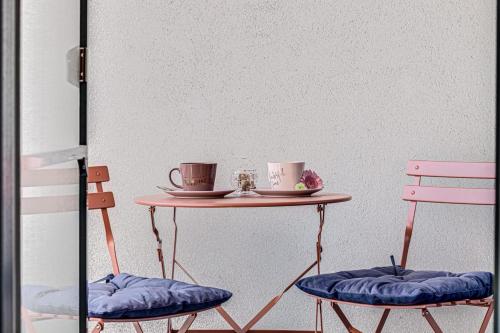 two cups on a table with two chairs at ARI - ARED Luxurious Apartments with Balcony & Free Parking in Arad