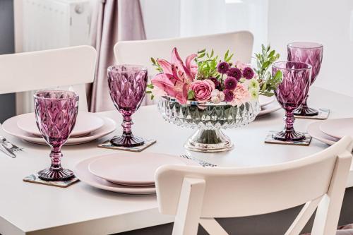 a dining room table with pink flowers in a vase at ARI - ARED Luxurious Apartments with Balcony & Free Parking in Arad