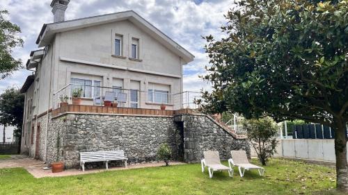 a house with two chairs and a bench in front of it at Casa Sinforiano in Santa Cruz de Bezana