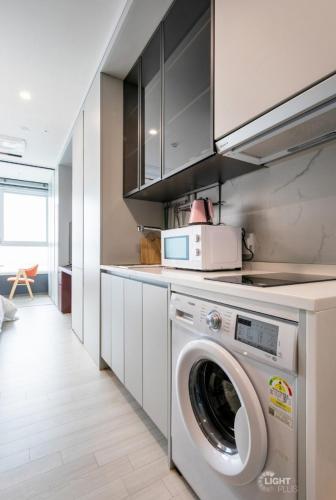 a kitchen with a washing machine and a microwave at Brand New Residence with Family in Busan