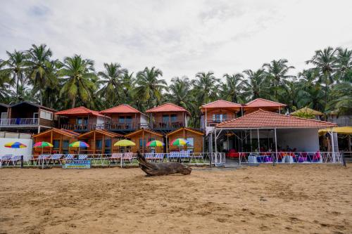 a row of houses on a beach with chairs and umbrellas at Om Sai Beach Resort in Agonda