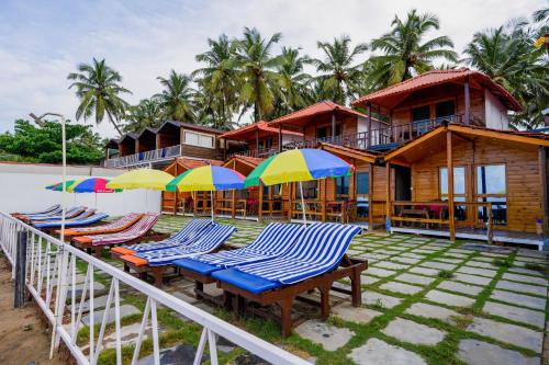 a resort with chairs and umbrellas in front of it at Om Sai Beach Resort in Agonda