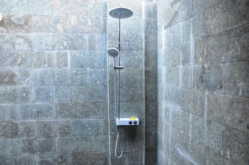 a shower in a bathroom with a stone wall at Kubudiuma Villas Bali in Canggu