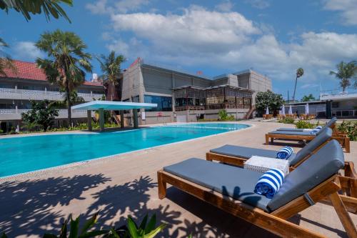 a pool with two lounge chairs next to a building at Kristal Hotel Kupang in Kupang