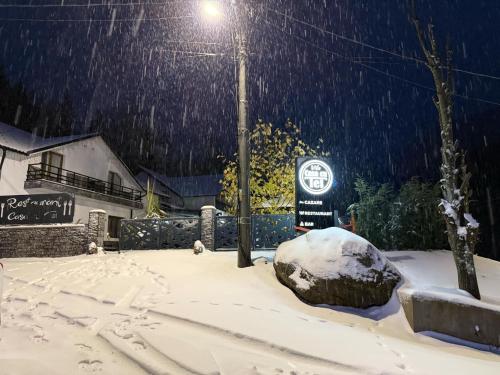 a snow covered street with a street light and a sign at Vila Casa cu Tei in Lupeni