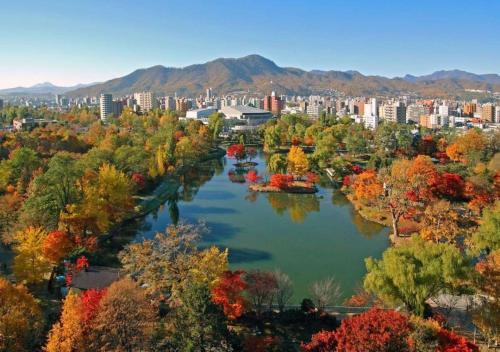 a river in the middle of a city with trees at Business Inn Norte in Sapporo